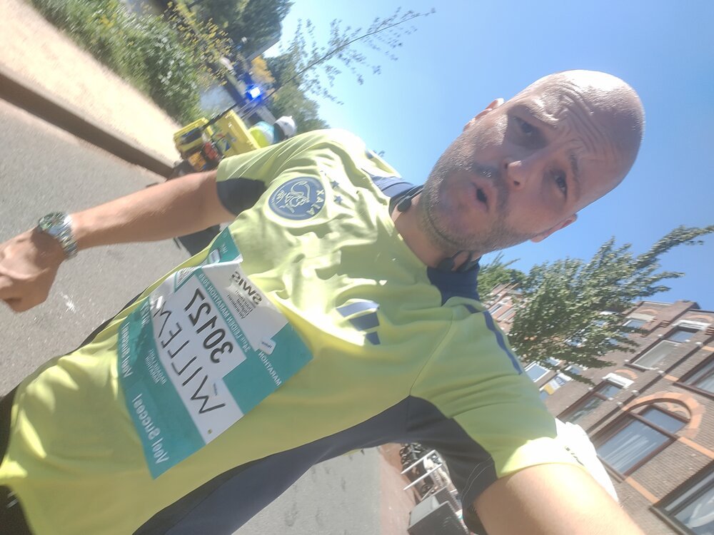 The event in one image: Pushing through exhaustion at the 40KM mark during the 2025 Leiden Marathon. Note the ambulance motorcycle in the background, and the fogged camera lens, blurred by sweat and the water I poured over myself to stay cool.