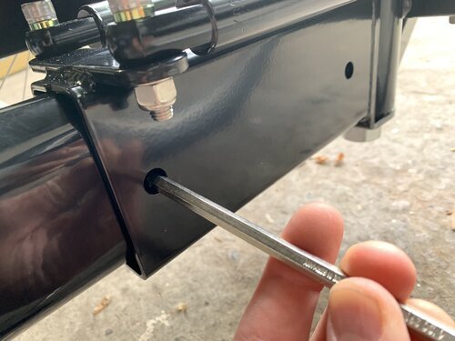 Usando una llave hexagonal para empujar la placa de relleno a su posición, liberando el orificio del perno